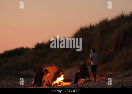 Feux de camp d'été sur la plage de Llangennith, péninsule de Gower, près de Swansea, Royaume-Uni. Remarque : les images peuvent présenter une légère douceur et un certain bruit de signal, tel qu'il est pris avec des paramètres ISO très élevés. Ne convient pas à une reproduction plus large. Banque D'Images