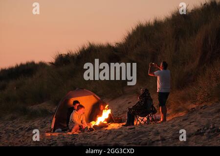 Feux de camp d'été sur la plage de Llangennith, péninsule de Gower, près de Swansea, Royaume-Uni. Remarque : les images peuvent présenter une légère douceur et un certain bruit de signal, tel qu'il est pris avec des paramètres ISO très élevés. Ne convient pas à une reproduction plus large. Banque D'Images