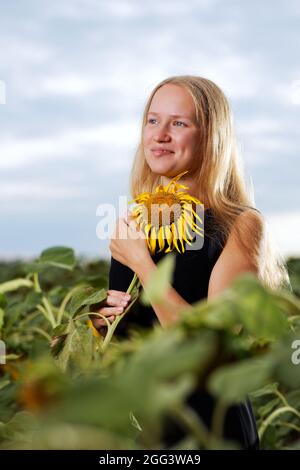 Potrait de fille avec tournesol entre le champ sur fond flou Banque D'Images