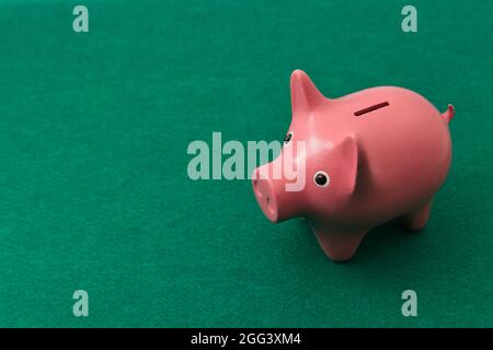 Gros plan d'une banque de porc sur une table avec un tapis de jeu vert avec un espace de copie à gauche Banque D'Images