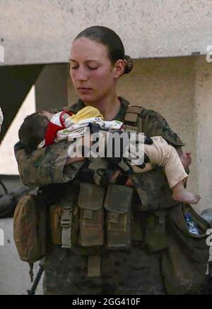 Une femme identifiée comme le sergent Nicole Gee du corps des Marines des États-Unis de Roseville, Calif, se tient alors qu'elle et d'autres membres du service militaire réconfortent les nourrissons à l'aéroport international Hamid Karzaï de Kaboul, en Afghanistan, dans une photo publiée sur Twitter le 20 août 2021. Sgt. Gee faisait partie des 13 membres du service américain tués lors d'un attentat terroriste. Crédit: Département de la Défense via CNP Banque D'Images