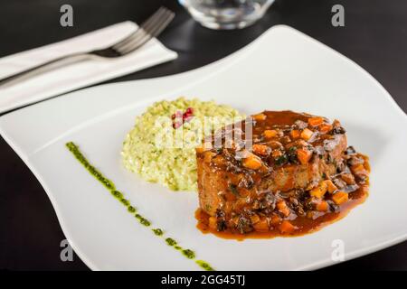 Filet de bœuf et risotto au basilic sur une assiette en porcelaine Banque D'Images