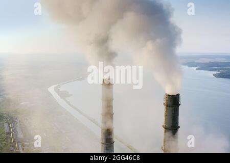 Vue aérienne des tuyaux hauts de la centrale au charbon avec de la fumée noire qui se déplace vers le haut de l'atmosphère polluante au lever du soleil Banque D'Images
