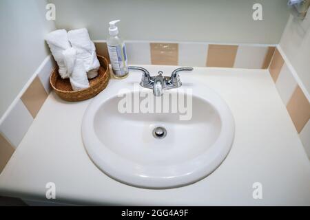 lavabo blanc de salle de bains avec carrelage vintage et serviettes de toilette organisées roulées dans la salle de bains des invités de vieux cottage. Banque D'Images