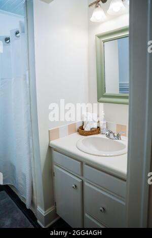 lavabo blanc de salle de bains avec carrelage vintage et serviettes de toilette organisées roulées dans la salle de bains des invités de vieux cottage. Banque D'Images