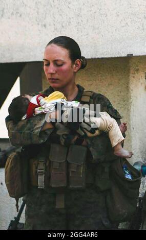 Sgt. Marine Nicole Gee affectée à la 24e unité expéditionnaire maritime (UMM) calme les nourrissons lors d'une évacuation à l'aéroport international Hamid Karzaï, Kaboul, Afghanistan, août 20. Les membres du service américain et les partenaires de la coalition aident le ministère d'État à effectuer une opération d'évacuation non combattantes (NEO) en Afghanistan. (É.-U. Photo du corps marin par Sgt. Isaiah Campbell) Gee était l'un des 13 Américains tués en action par un attentat suicide ISIS-K. Banque D'Images