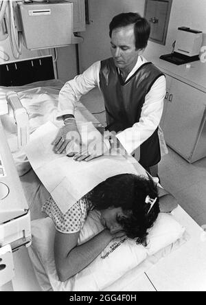 Austin Texas USA, vers 1992: Un radiologiste portant un gilet de protection en plomb prépare la patiente à l'examen du myélogramme de la moelle épinière et des nerfs. ©Bob Daemmrich Banque D'Images