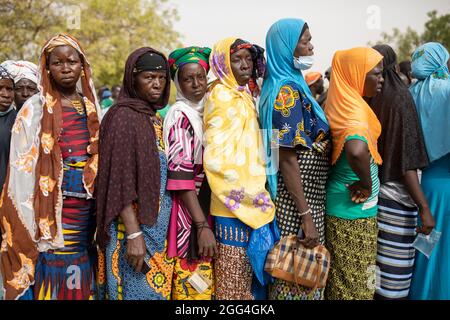 Les femmes se font la queue pour recevoir une aide alimentaire dans un centre de distribution de camps de déplacés à Nouna, Burkina Faso, Afrique de l'Ouest. Banque D'Images