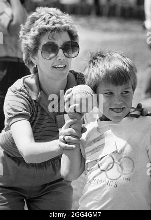 Austin Texas USA, 1991 : une bénévole féminine aide un garçon de troisième année à lancer une balle pendant la journée de jeu à l'école primaire. ©Bob Daemmrich Banque D'Images