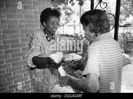 Austin Texas USA, 1989 : bénévole femelle noire Meals on Wheels qui travaille chez IBM livre de la nourriture à des clients âgés. ©Bob Daemmrich Banque D'Images