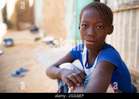 Portrait d'une jeune fille de 11 ans assise à l'extérieur de sa maison dans la région de Ségou, Mali, Afrique de l'Ouest. Banque D'Images