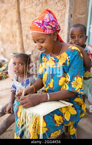 Une mère Fulani déménage à la main des matts et des fans de palmier séché pour assurer la subsistance de sa famille dans la région de Ségou, Mali, Afrique de l'Ouest. Banque D'Images