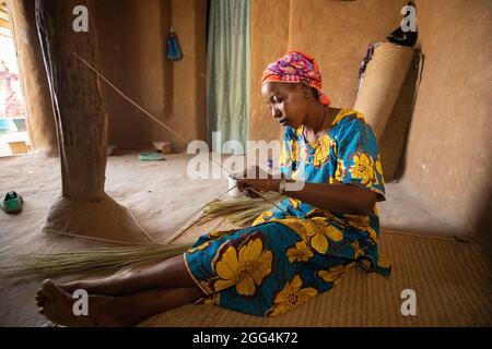 Une femme Fulani déménage à la main des matts et des fans de palmier séché pour la subsistance de sa famille dans la région de Ségou, Mali, Afrique de l'Ouest. Banque D'Images