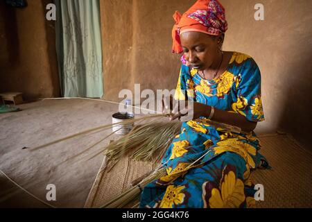 Une femme Fulani déménage à la main des matts et des fans de palmier séché pour la subsistance de sa famille dans la région de Ségou, Mali, Afrique de l'Ouest. Banque D'Images