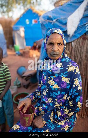 Le camp de Senou se trouve à la limite sud de Bamako, la capitale du Mali. C'est l'un des huit camps informels autour de la ville et, en soi, il abrite 223 familles et un peu plus de 1 000 personnes déplacées. Les familles qui vivent ici ont fui la violence et l'insurrection dans le nord et le centre du pays. Parce que la plupart d'entre eux n'ont pas de moyens de revenu ou de source régulière de nourriture, la faim est un défi quotidien et la malnutrition de sa population reste endémique. Ici, Soumai Tali se trouve à l’extérieur du refuge de fortune de sa famille. Banque D'Images