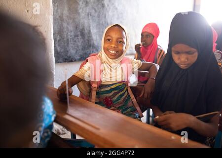 Le camp de Senou se trouve à la limite sud de Bamako, la capitale du Mali. C'est l'un des huit camps informels autour de la ville et, en soi, il abrite 223 familles et un peu plus de 1 000 personnes déplacées. Les familles qui vivent ici ont fui la violence et l'insurrection dans le nord et le centre du pays. Parce que la plupart d'entre eux n'ont pas de moyens de revenu ou de source régulière de nourriture, la faim est un défi quotidien et la malnutrition de sa population reste endémique. Ici, les enfants écrivent sur des lattes de craie dans la seule école primaire du camp, enseignée par Mme Asmatou Coulibably. Banque D'Images