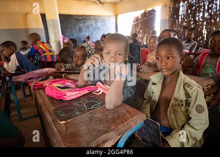 Le camp de Senou se trouve à la limite sud de Bamako, la capitale du Mali. C'est l'un des huit camps informels autour de la ville et, en soi, il abrite 223 familles et un peu plus de 1 000 personnes déplacées. Les familles qui vivent ici ont fui la violence et l'insurrection dans le nord et le centre du pays. Parce que la plupart d'entre eux n'ont pas de moyens de revenu ou de source régulière de nourriture, la faim est un défi quotidien et la malnutrition de sa population reste endémique. Ici, les enfants apprennent dans la seule école primaire du camp, enseignée par Mme Asmatou Coulibably. Banque D'Images