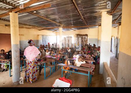 Le camp de Senou se trouve à la limite sud de Bamako, la capitale du Mali. C'est l'un des huit camps informels autour de la ville et, en soi, il abrite 223 familles et un peu plus de 1 000 personnes déplacées. Les familles qui vivent ici ont fui la violence et l'insurrection dans le nord et le centre du pays. Parce que la plupart d'entre eux n'ont pas de moyens de revenu ou de source régulière de nourriture, la faim est un défi quotidien et la malnutrition de sa population reste endémique. Ici, les enfants apprennent dans la seule école primaire du camp, enseignée par Mme Asmatou Coulibably. Banque D'Images