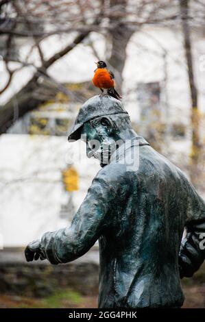 Un robin se dresse au-dessus de la statue de Fred Lebow, fondateur du marathon de New York, à Central Park, New York, États-Unis. Banque D'Images