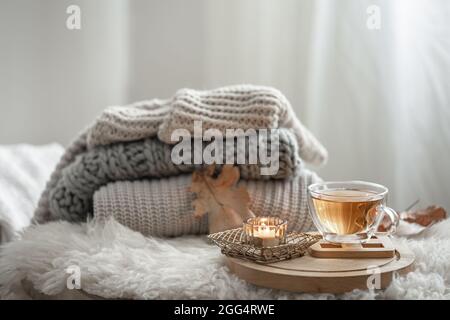 Maison encore vie avec des pulls tricotés et une tasse de thé sur un fond flou. Banque D'Images