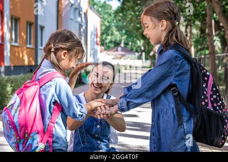 Une jeune femme soutient moralement les filles qui tiennent la main encourage les enfants, accompagne les élèves à l'école. Banque D'Images