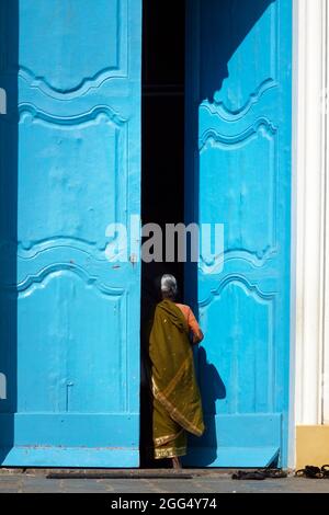 Titre femme indienne portant une saree entrant par une grande porte bleue Banque D'Images