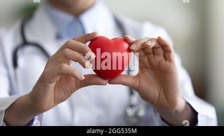 Gros plan jeune femme médecin tenant le coeur figure dans les mains. Banque D'Images