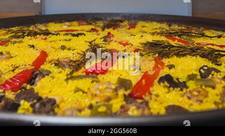 Gros plan d'une paella cuite à la maison avec du riz, du poivron rouge, des haricots verts, de la viande de poulet et de lapin, des champignons et d'autres ingrédients, aromatisés W Banque D'Images