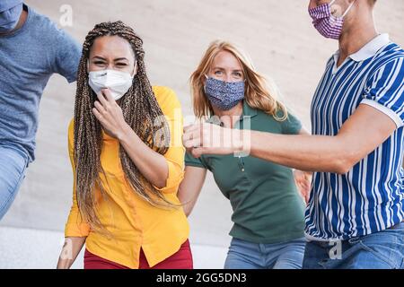 Jeunes multiraciaux ayant l'amusement portant un masque de sécurité en plein air dans la ville - Focus sur le visage de fille africaine Banque D'Images