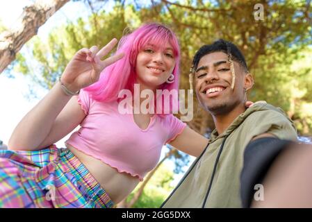 autre couple divers traînant ensemble froid et souriant assis dans un parc posant et prenant un portrait de selfie de pov. amis heureux Banque D'Images