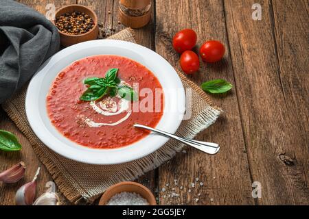 Soupe de tomates maison au basilic et à la crème sur fond de bois. Alimentation saine et biologique. Banque D'Images