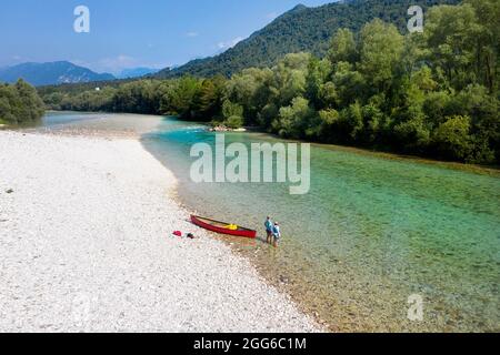 Vue aérienne de la mère et du fils debout dans les eaux peu profondes par un canot rouge sur la rivière Soca près de Tolmin, Slovénie Banque D'Images
