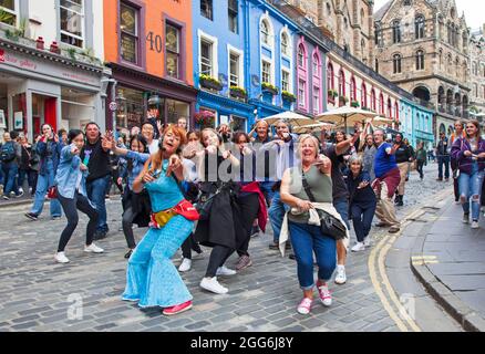 Victoria Street, centre-ville d'Édimbourg, Écosse, Royaume-Uni. 29 août 2021. La Madame Cha Cha, colorée et animée, mène une amusante visite interactive à pied de la discothèque Silent en « Guru Dudu » dans les rues de la vieille ville. La visite à pied fait partie du Festival Fringe d'Édimbourg qui se termine demain. Crédit : Arch White/Alamy Live News. Banque D'Images