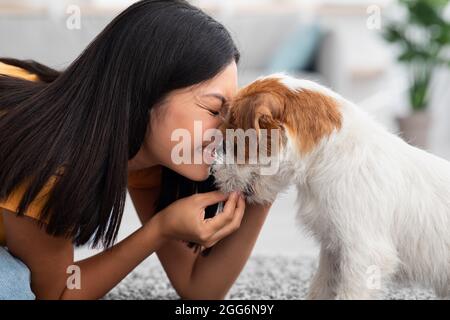 Une femme asiatique heureuse qui pète son joli chien à la maison Banque D'Images