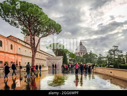 Personnes fortuites sur la terrasse du Musée du Vatican, donnant sur le dôme de la basilique Saint-Pierre. Jour de pluie, ciel spectaculaire, reflets sur le marbre. Banque D'Images