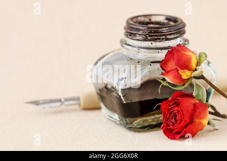 Inkwell, stylo et roses séchées sur fond de papier vintage. Copier l'espace. Banque D'Images