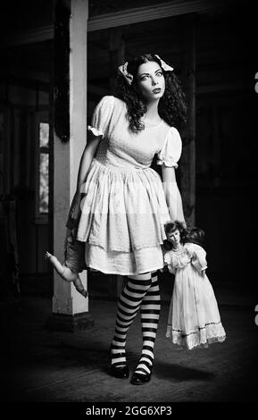 L'étrange fille avec des poupées dans les mains. Noir et blanc Banque D'Images