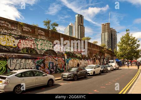 QUARTIER ARTISTIQUE ET CULTUREL DE LONDRES AUTOUR D'UNE RUELLE DE BRIQUES AVEC DES MOTIFS ET DES SLOGANS CRÉATIFS, SCLATER STREET WALL ET À PROXIMITÉ DE TOWER BLOCKS Banque D'Images