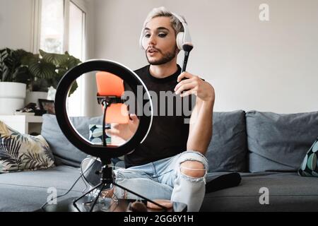 Gay man streaming en ligne maquillage vidéo tutorial avec téléphone mobile à l'intérieur à la maison - LGBT, Drag queen, technologie tendance concept - Focus dans le visage Banque D'Images