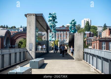 Tacoma, WA USA - vers août 2021 : vue sur les grandes sculptures et les touristes à l'extérieur du musée du verre en centre-ville, par une journée ensoleillée et sans nuages Banque D'Images