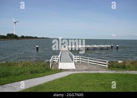 Jetée dans le lac Ijsselmeer près de la ville hollandaise de Medemblik en Hollande du Nord avec des moulins à vent en arrière-plan. Été, août Banque D'Images