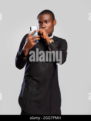 un jeune homme africain regardant son téléphone de surprise Banque D'Images