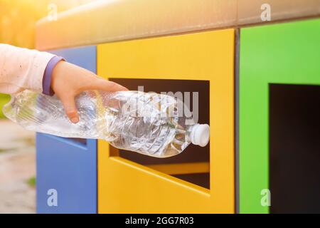 Poubelles de recyclage des déchets en plastique. Gros plan jeter la main bouteille plastique contenant de recyclage poubelle de tri poubelle de collecte. Main enfant mise Banque D'Images