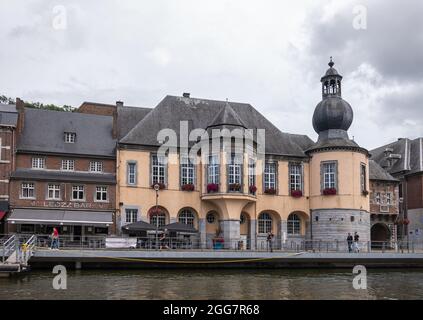 Dinant, Wallonie, Belgique - 8 août 2021 : hôtel de ville historique avec sa tour et ses restaurants et bars adjacents dans un paysage nuageux gris le long de la rive de la Meuse Banque D'Images