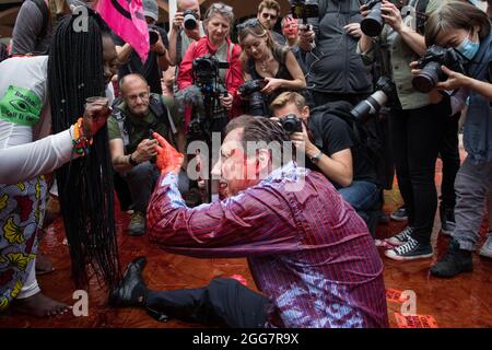 Londres, Royaume-Uni. 27 août 2021. Un activiste de la rébellion d'extinction habillé comme un financier couvert de faux sang agit une querelle raciste avec le fondateur de United for Black Lives Marvina Newton sur la place Paternoster à la suite d'une marche de l'argent du sang à travers la ville de Londres. Extinction Rebellion avait l'intention de mettre en évidence les institutions financières qui financent des projets de combustibles fossiles, en particulier dans les pays du Sud, ainsi que les cabinets d'avocats et les institutions qui les facilitent, tout en appelant le gouvernement britannique à cesser tous les nouveaux investissements dans les combustibles fossiles avec effet immédiat. Crédit : Mark Kerrison/Alamy Live News Banque D'Images