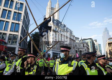 Londres, Royaume-Uni. 27 août 2021. Les militants écologistes de la rébellion d'extinction utilisent trois trépieds pour bloquer une jonction à l'extérieur de la station de métro Mansion House à la suite d'une marche de l'argent du sang dans la ville de Londres le cinquième jour de manifestations impossibles de la rébellion. Extinction Rebellion avait l'intention de mettre en évidence les institutions financières qui financent des projets de combustibles fossiles, en particulier dans les pays du Sud, ainsi que les cabinets d'avocats et les institutions qui les facilitent, tout en appelant le gouvernement britannique à cesser tous les nouveaux investissements dans les combustibles fossiles avec effet immédiat. Crédit : Mark Kerrison/Alamy Live News Banque D'Images