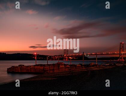 Une photo de la côte au parc Hidden Beach à Tacoma, Washington. L'image est une longue exposition prise au coucher du soleil face au pont de Tacoma Narrows Banque D'Images