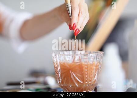 La main tire une brosse d'un verre d'eau Banque D'Images