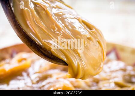 dulce de leche ou caramel maison s'égoutter d'une cuillère en bois, macro photo de la nourriture Banque D'Images