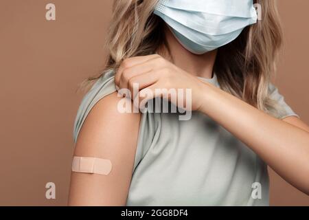 Campagne de vaccination contre la maladie de Covid-19: La femme dans le masque médical montre bras obtenant le vaccin Banque D'Images